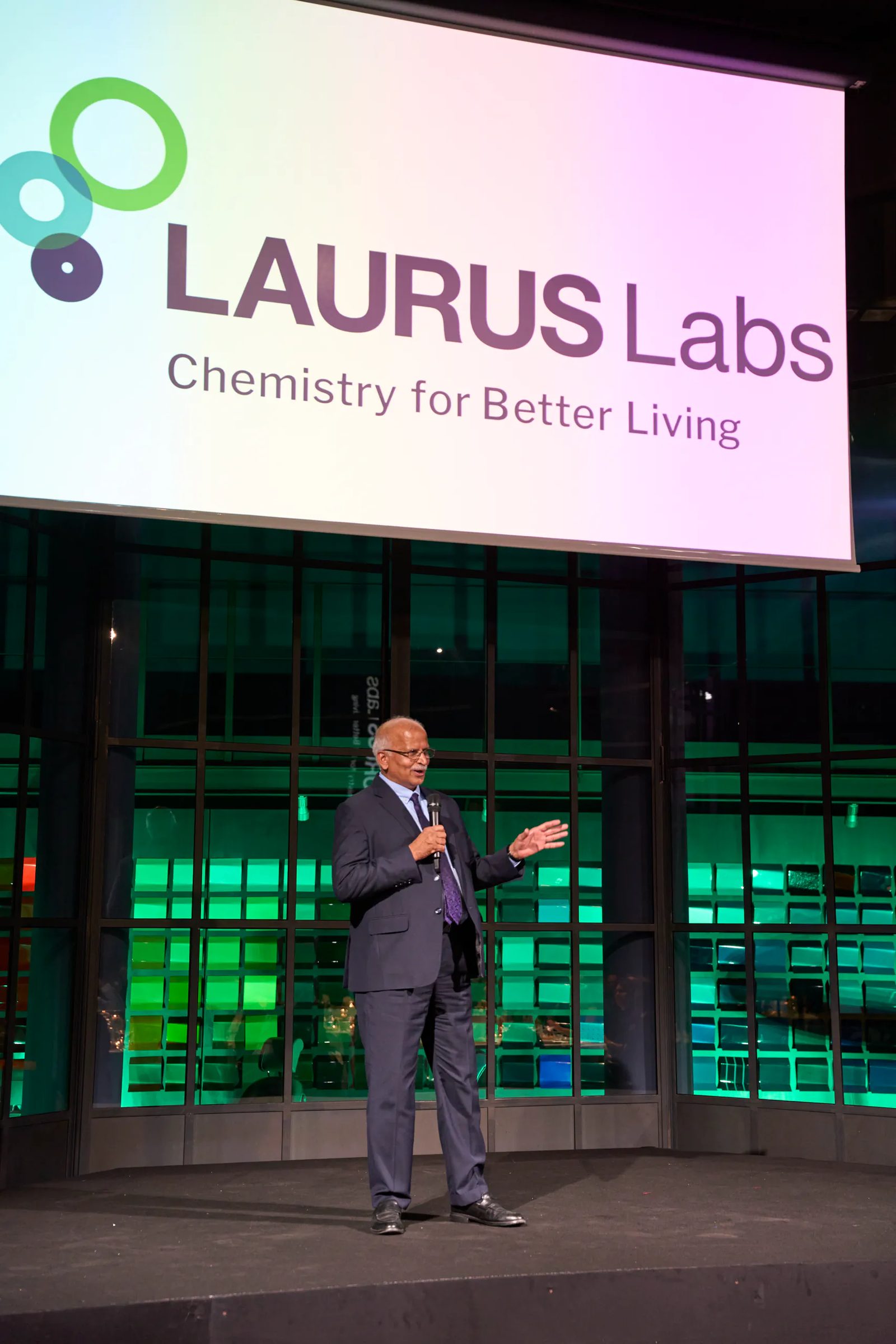 Speaker on stage in front of Laurus Labs branding