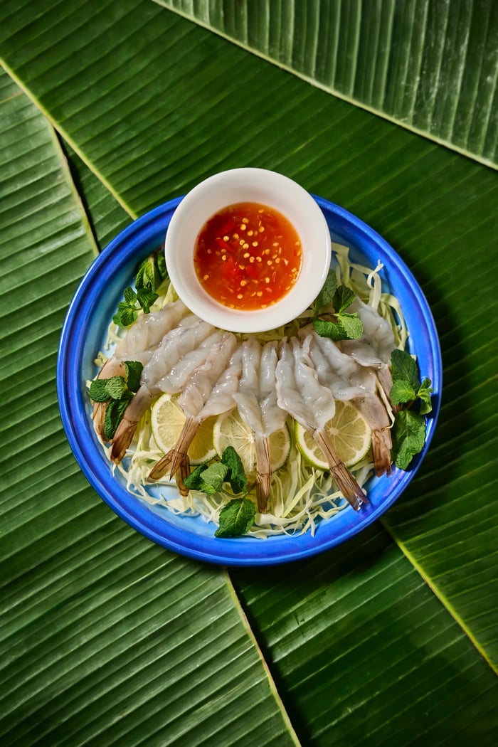 Gamberi crudi con salsa piccante e lime su piatto blu e foglie di banana — fotografia cucina thai, ristorante etnico Milano