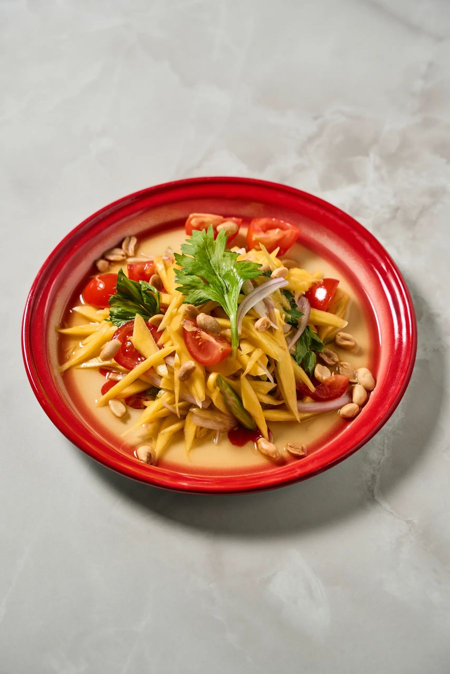 Som tam insalata di mango verde con arachidi e pomodorini in piatto rosso — cucina tailandese, fotografo food ristorante etnico Milano