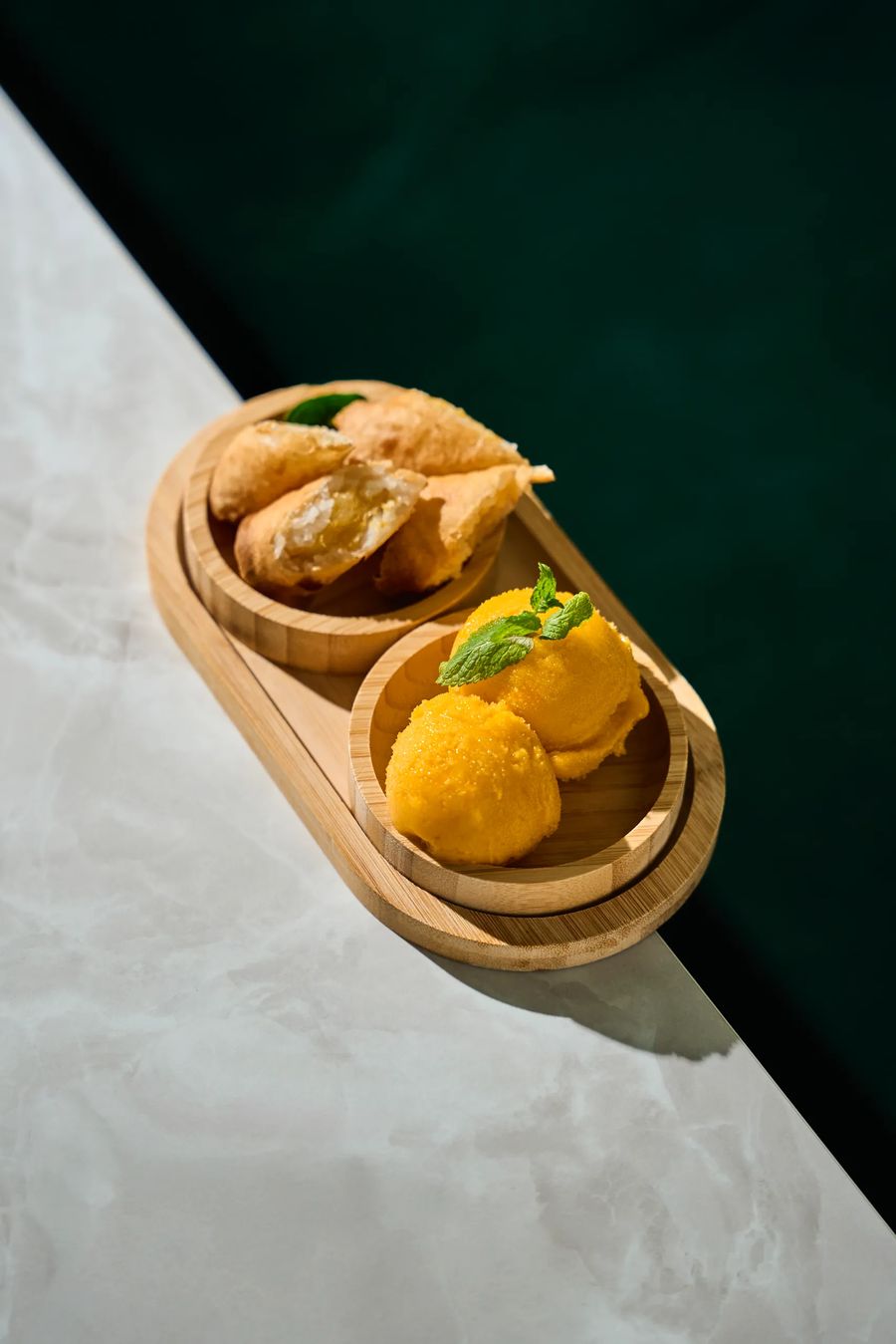 Spring roll fritti con gelato al mango su vassoio di bambù, sfondo verde scuro — fotografo cibo ristorante Thai Lounge Milano