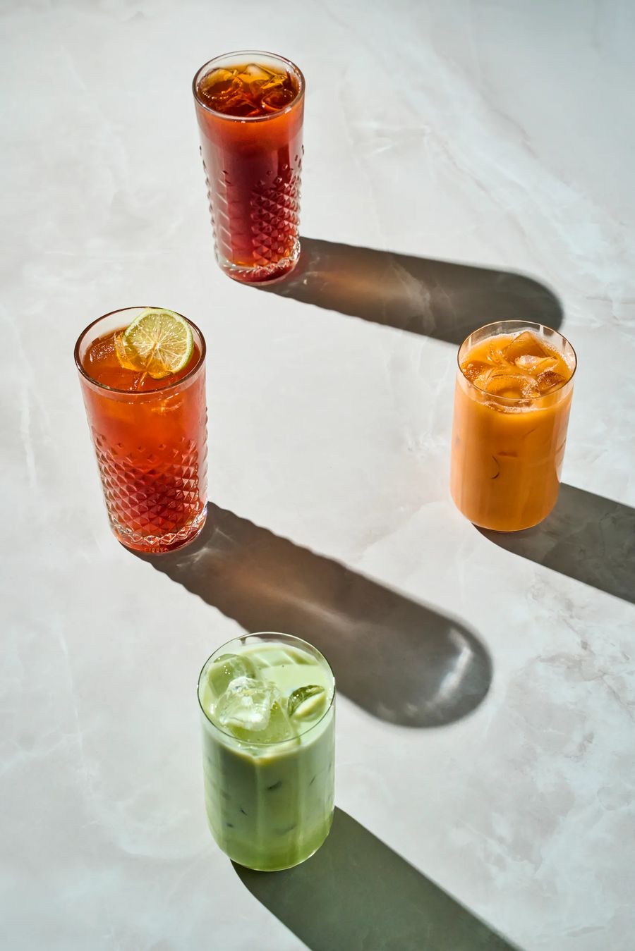 Quattro bevande thai fredde: tè rosso, thai tea con lime, thai tea e matcha latte — drink photography Thai Lounge Milano