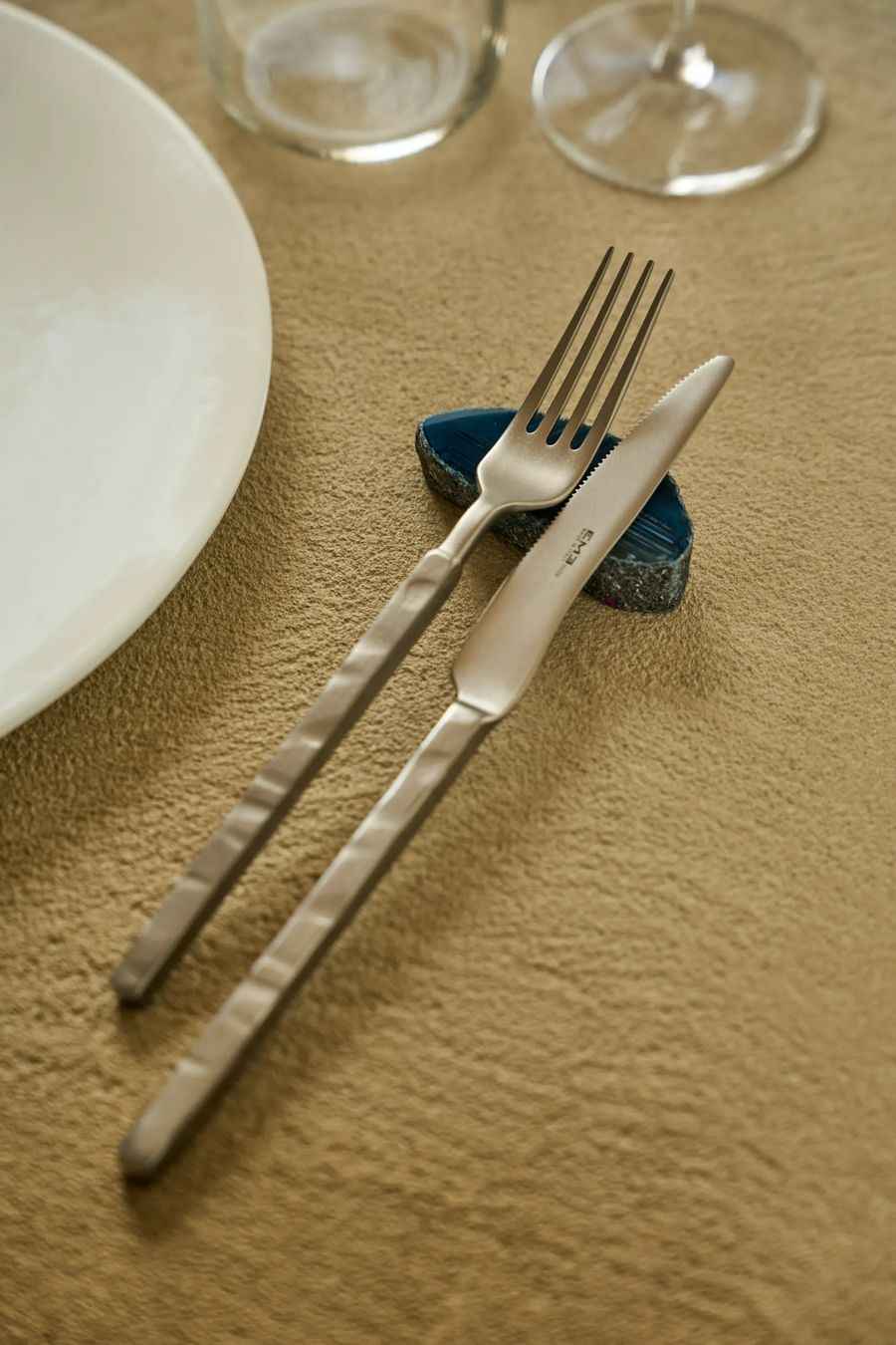 Posate di design su portaposate in agata blu e tovaglietta sabbia — mise en place raffinata, fotografo dettagli ristorazione Milano