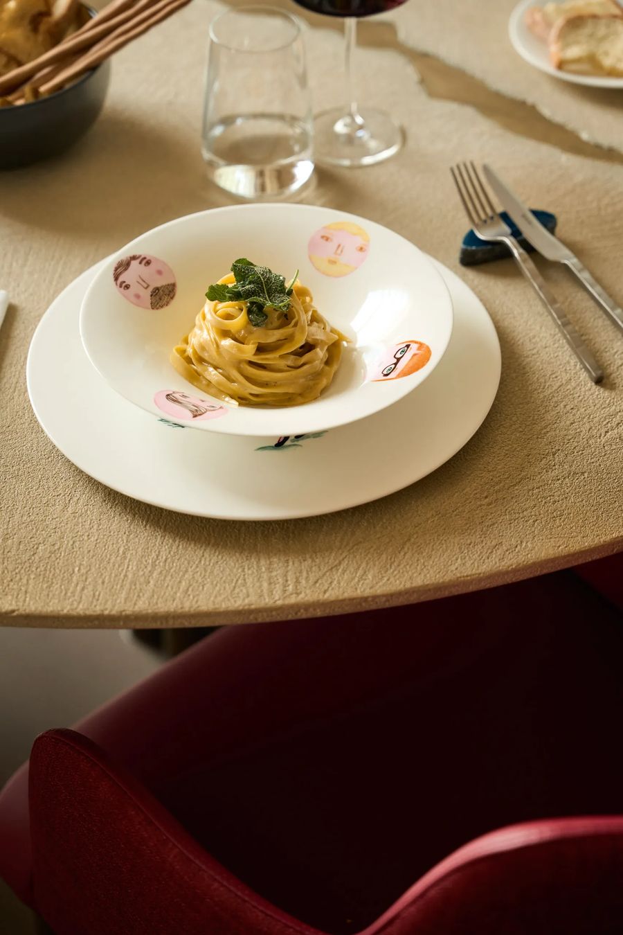 Tagliatelle al burro e salvia sul tavolo del ristorante con piatto illustrato e posate di design — fotografia food FATA Milano