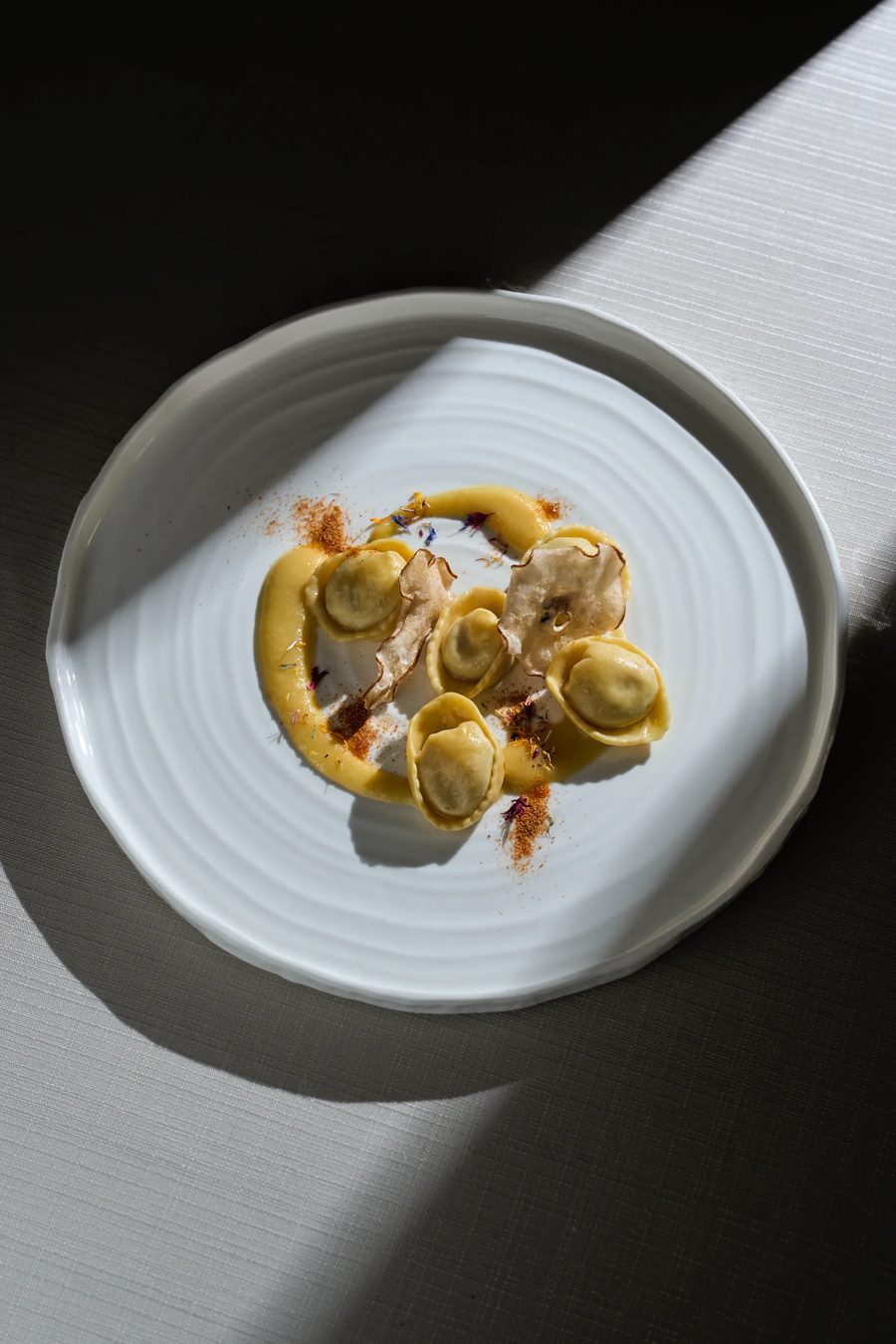 Tortellini con crema allo zafferano e tartufo a lamelle su piatto ondulato — pasta ripiena fine dining, fotografo gastronomia Milano
